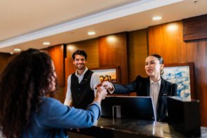 Young receptionist woman giving key card to guest at hotel